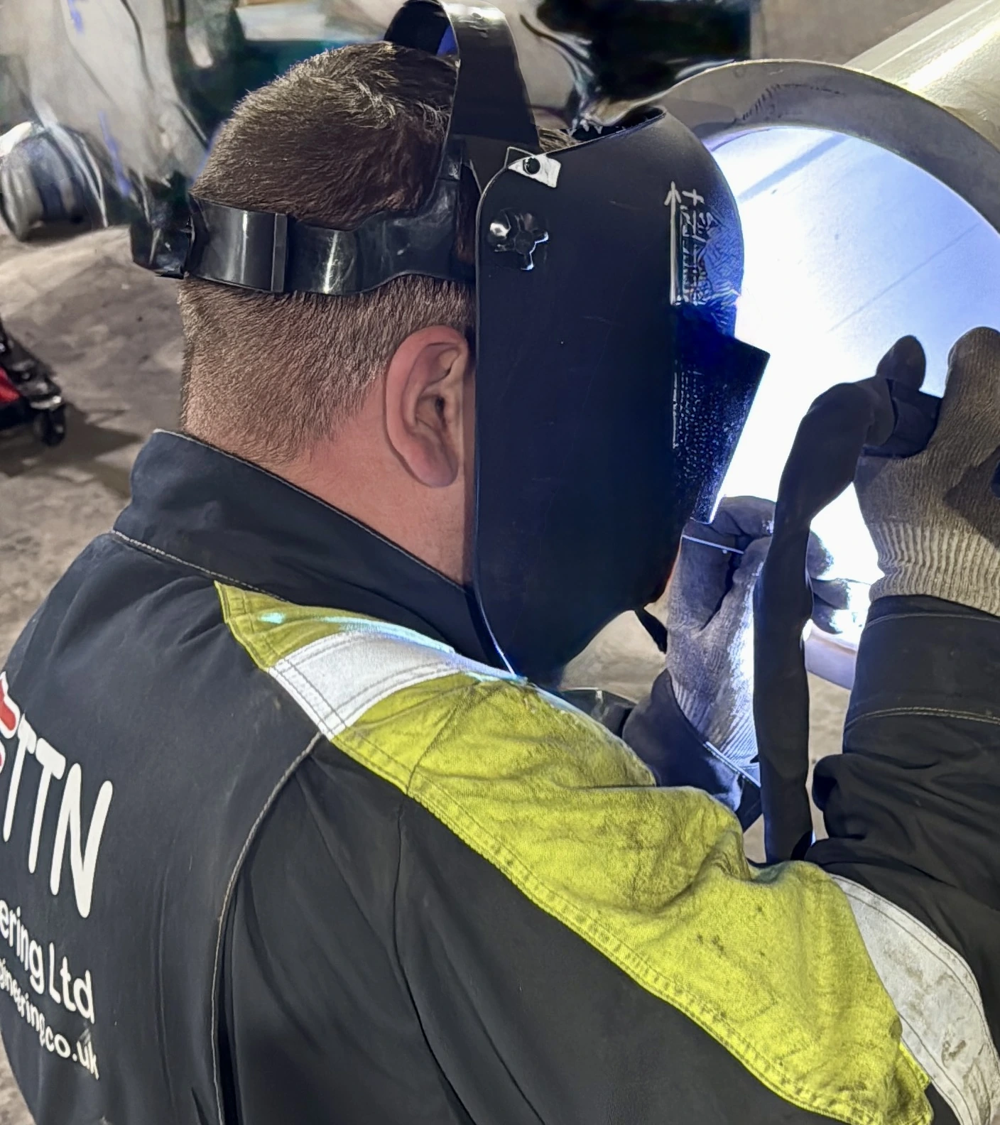 TTN operative in branded workwear welding pipework in the workshop